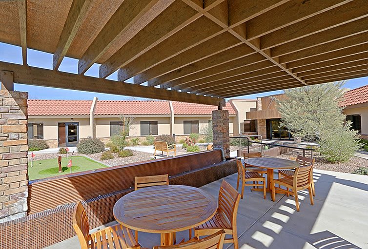 A courtyard with wooden outdoor furniture and a pergola on a sunny day.