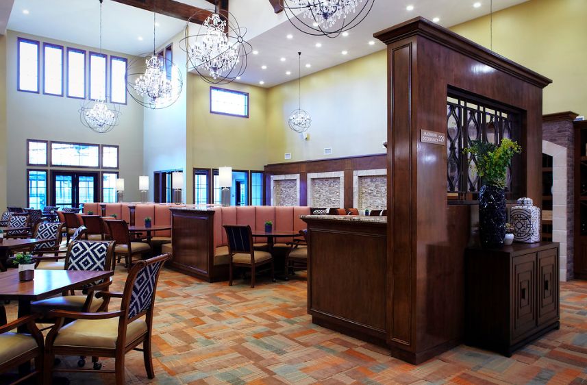 A spacious restaurant interior with elegant chandeliers, cozy booths, and wooden furnishings.