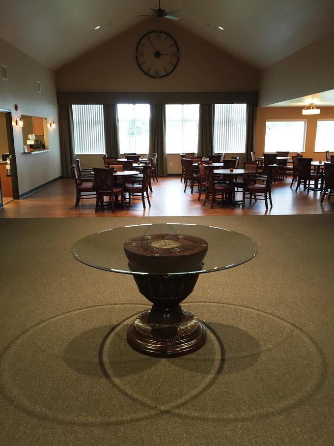A spacious dining area with multiple tables and chairs, featuring a central glass-top table.