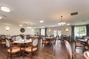 A spacious dining room with neatly arranged tables and chairs, featuring elegant lighting and a wooden floor.