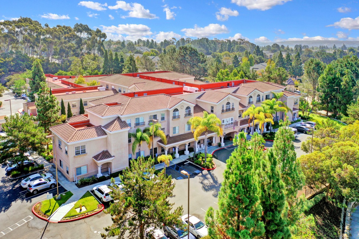 Aerial view of a residential building surrounded by trees and a parking lot.