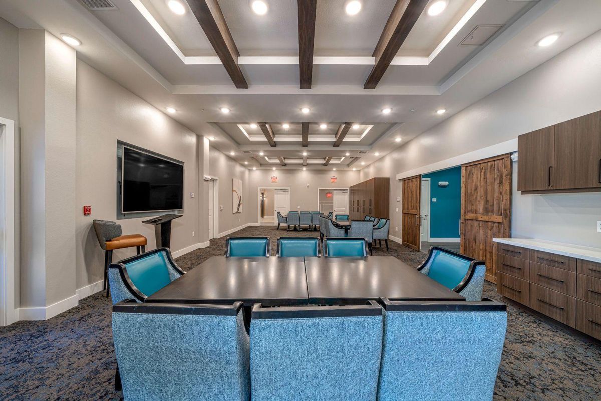 A spacious and modern conference room featuring comfortable seating, a large screen, and stylish ceiling lighting.