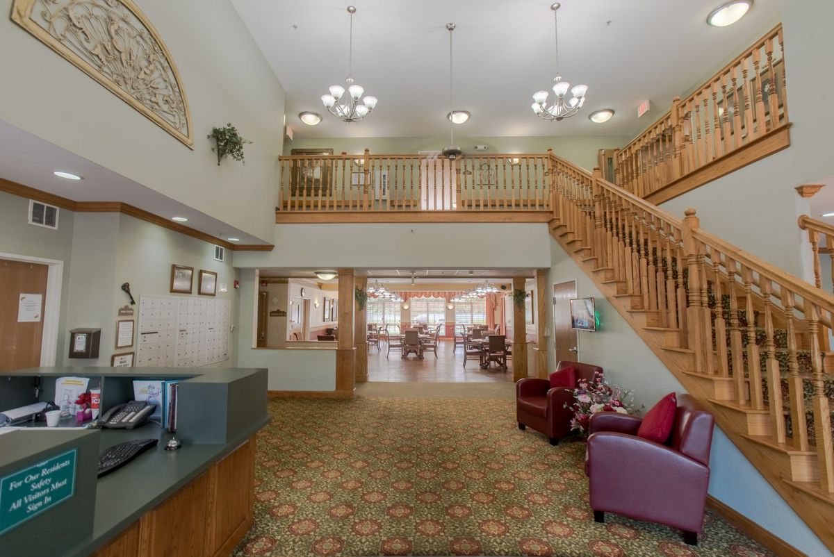 Spacious lobby area with a wooden staircase and elegant chandeliers.