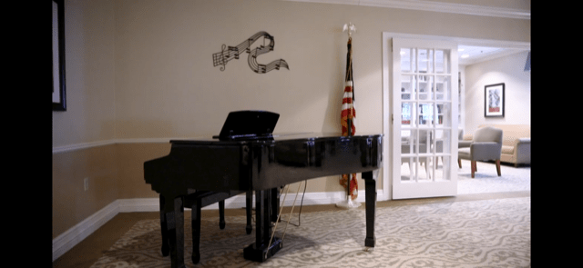 A grand piano in a music room with an American flag and sheet music decor on the wall.