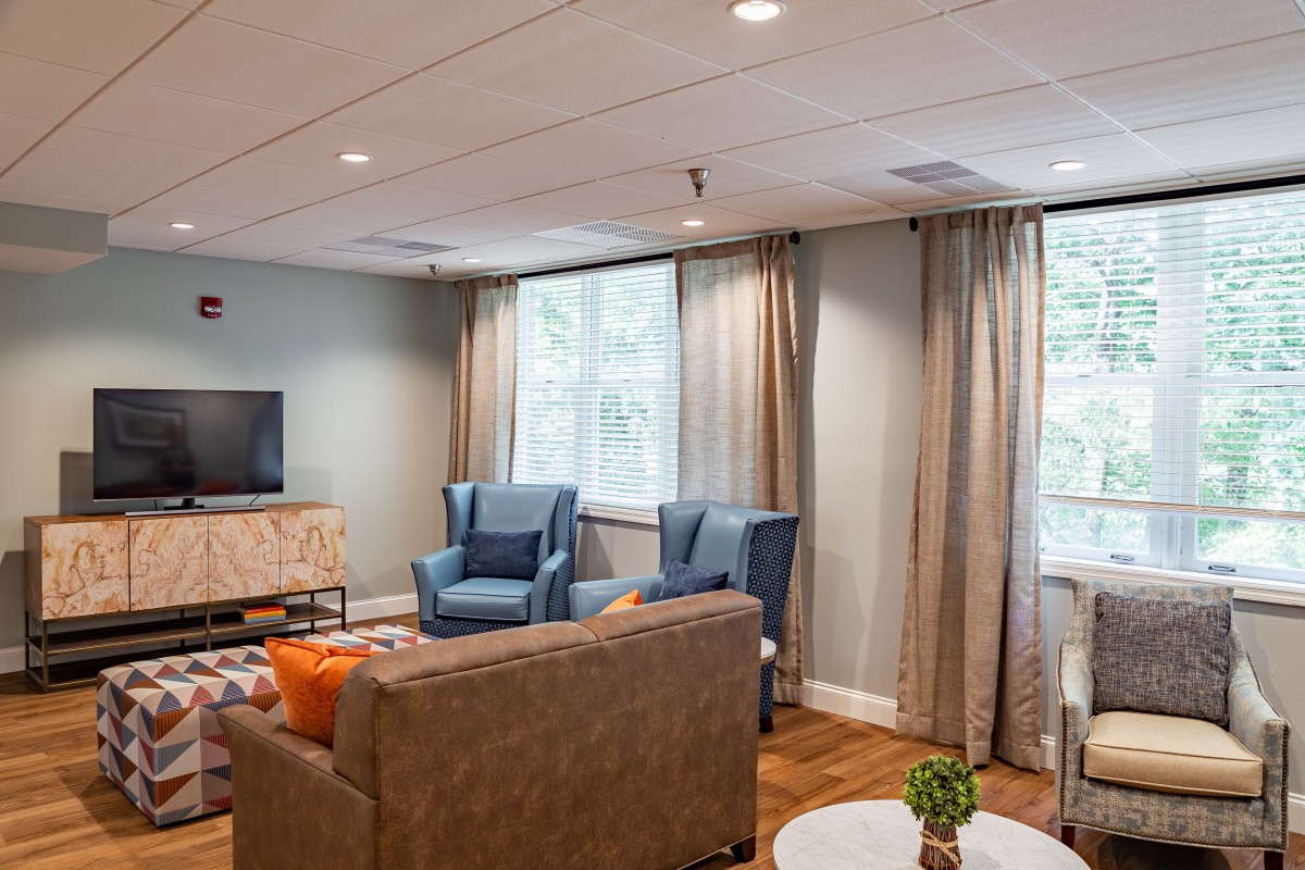 A cozy living room with plush seating and a television, featuring large windows and elegant curtains.