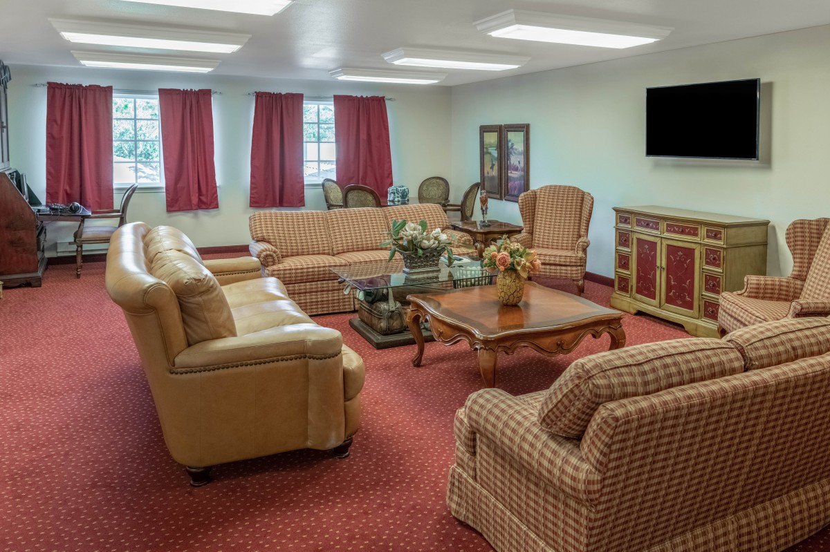 A traditional living room with multiple sofas, armchairs, a coffee table, and a television.