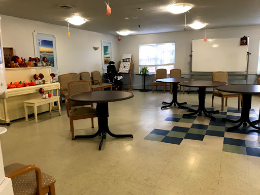 A spacious community room featuring tables and chairs arranged for group activities.
