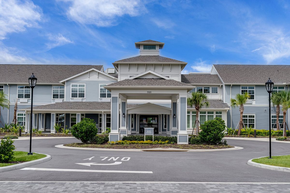 A modern residential building with a grand entrance under a blue sky.
