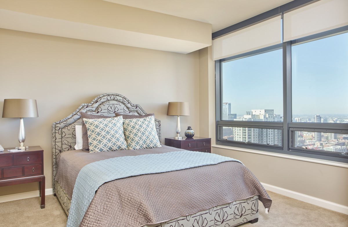 A modern bedroom with a large window offering a city view.