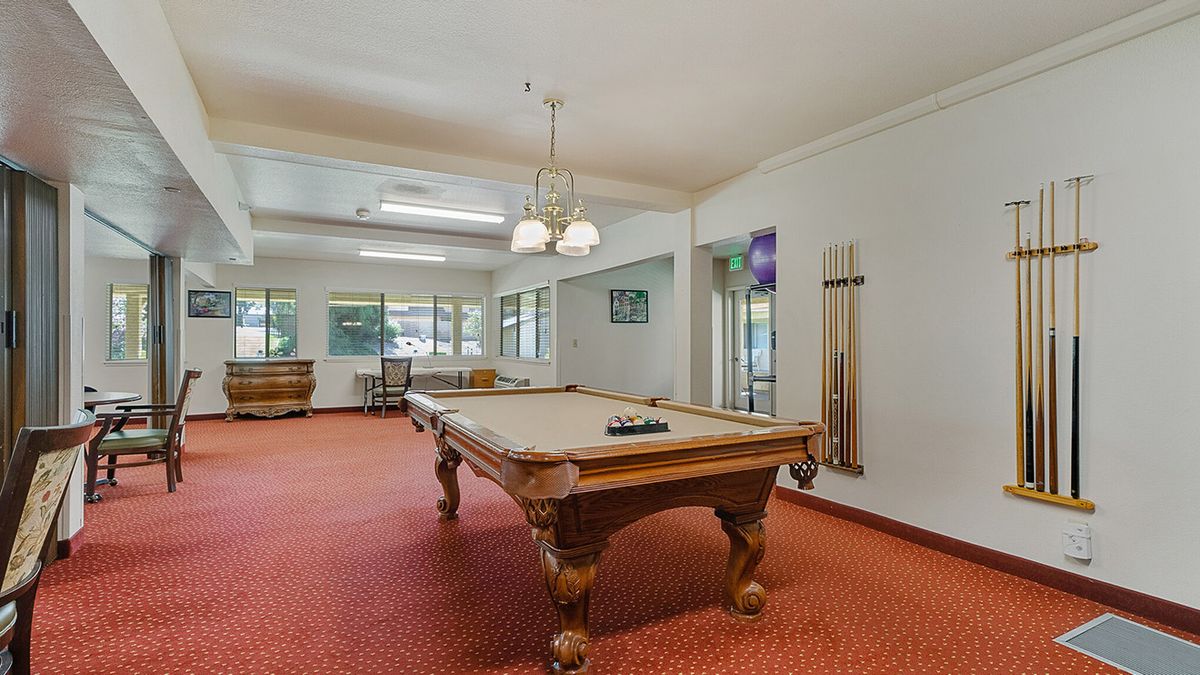 A spacious game room featuring a classic pool table with a red carpet and comfortable seating.