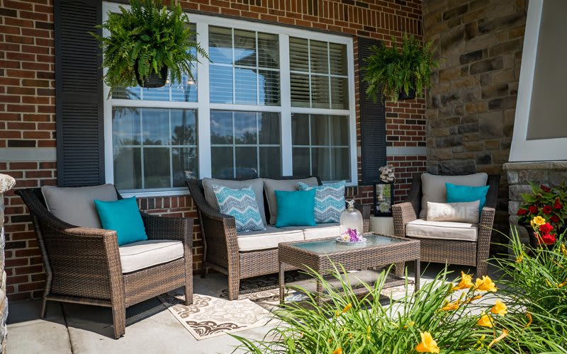 A cozy patio with wicker furniture and colorful cushions, complemented by hanging plants.