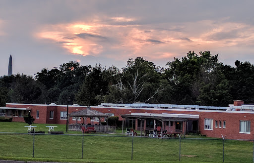 A school building surrounded by greenery under a beautiful sunset.