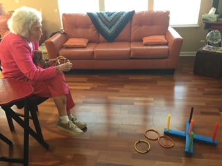 An elderly person playing a ring toss game in the living room.