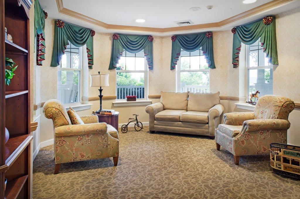 A cozy living room with elegant furniture and large windows adorned with curtains.