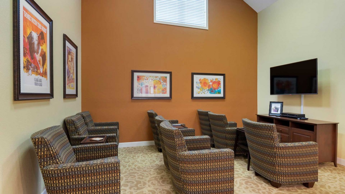 A waiting room with patterned chairs, an orange accent wall, and framed artwork.
