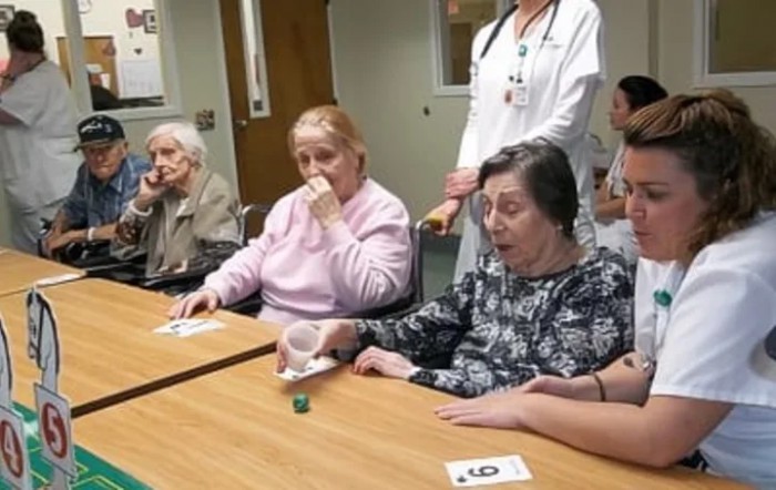 Elderly residents participating in a group activity at a nursing home with healthcare staff present.
