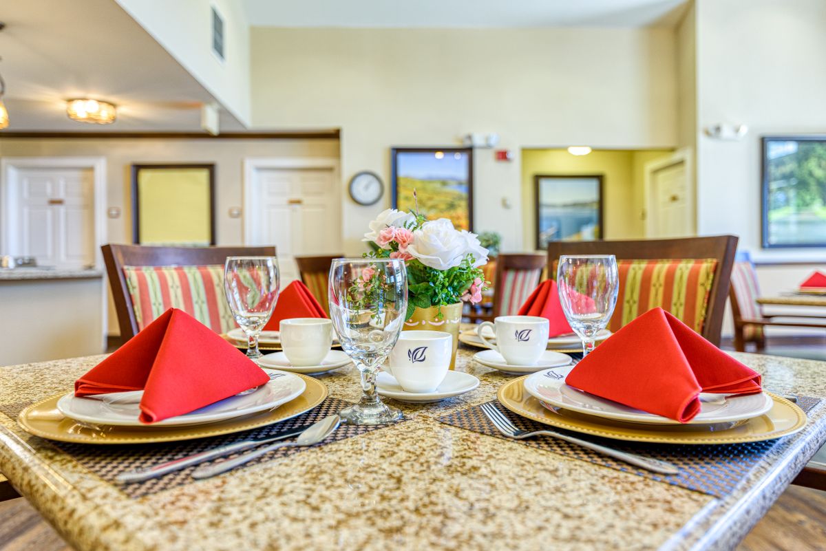 A neatly set dining table with red napkins and elegant dinnerware in a cozy indoor setting.