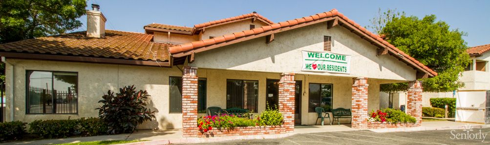 A storefront with brick pillars and a flower bed in front.