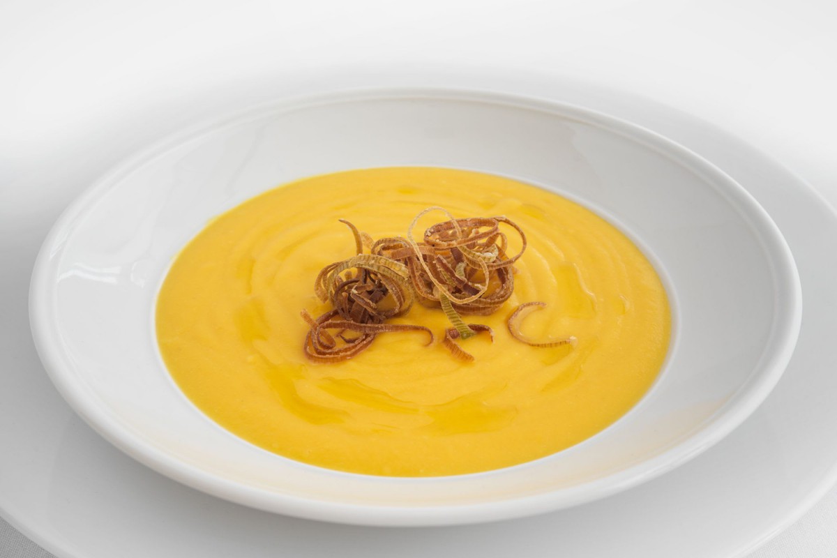 A creamy pumpkin soup garnished with crispy fried onions.