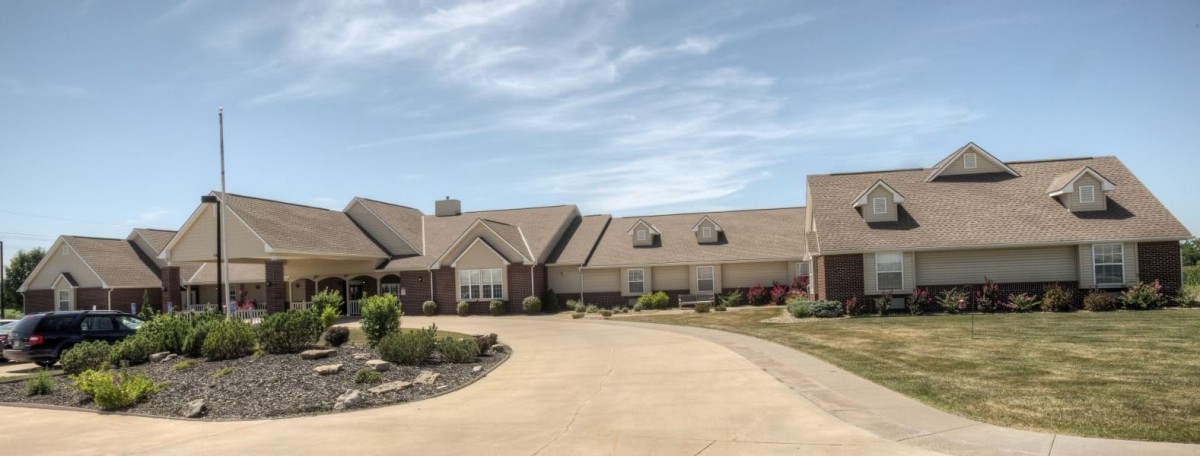 A spacious suburban mansion featuring a long driveway and well-maintained landscaping.