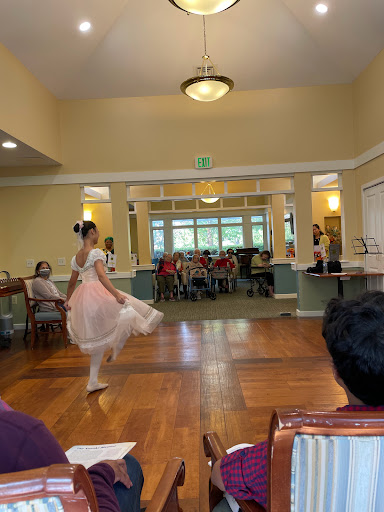 A young dancer gracefully performs a ballet piece in front of an audience at a community center.