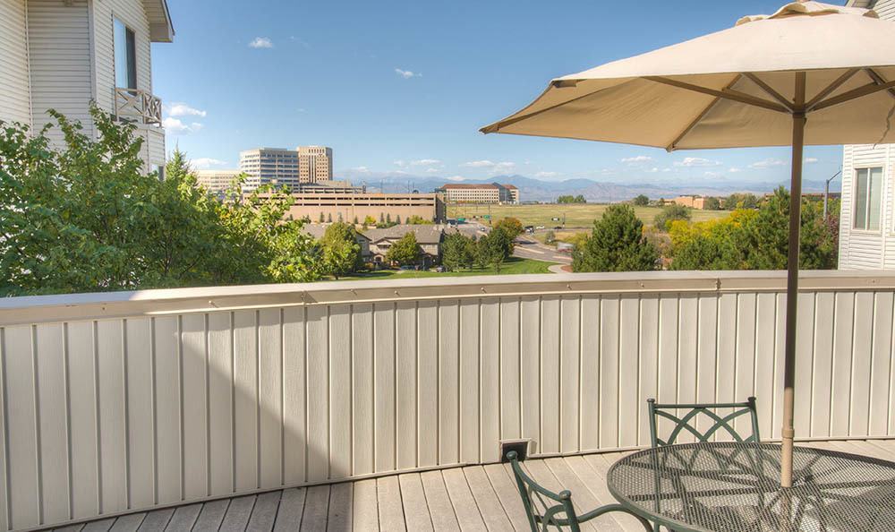 A deck with outdoor furniture and an umbrella overlooking a cityscape with mountains in the background.