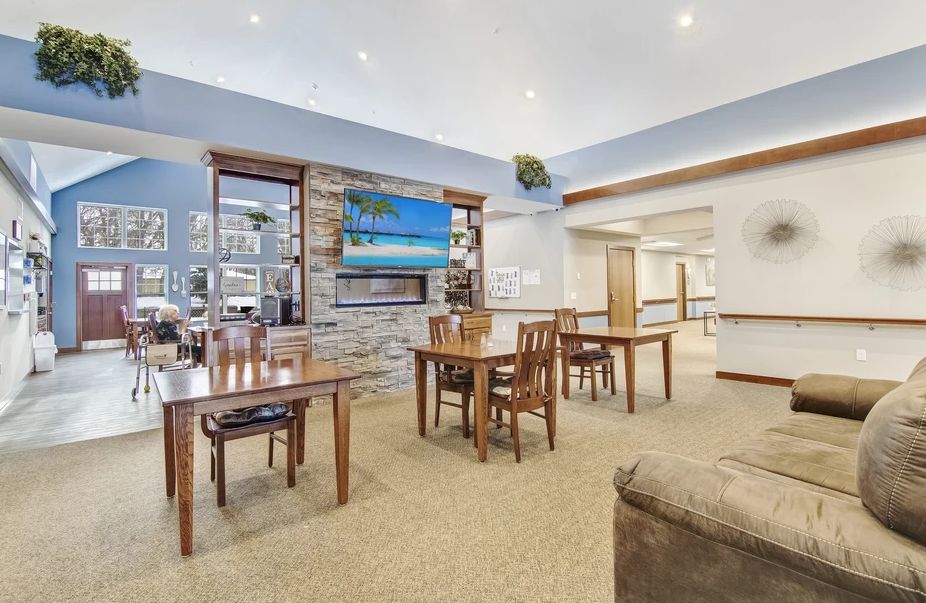 A cozy dining area with wooden tables and chairs, featuring a fireplace and a wall-mounted television.