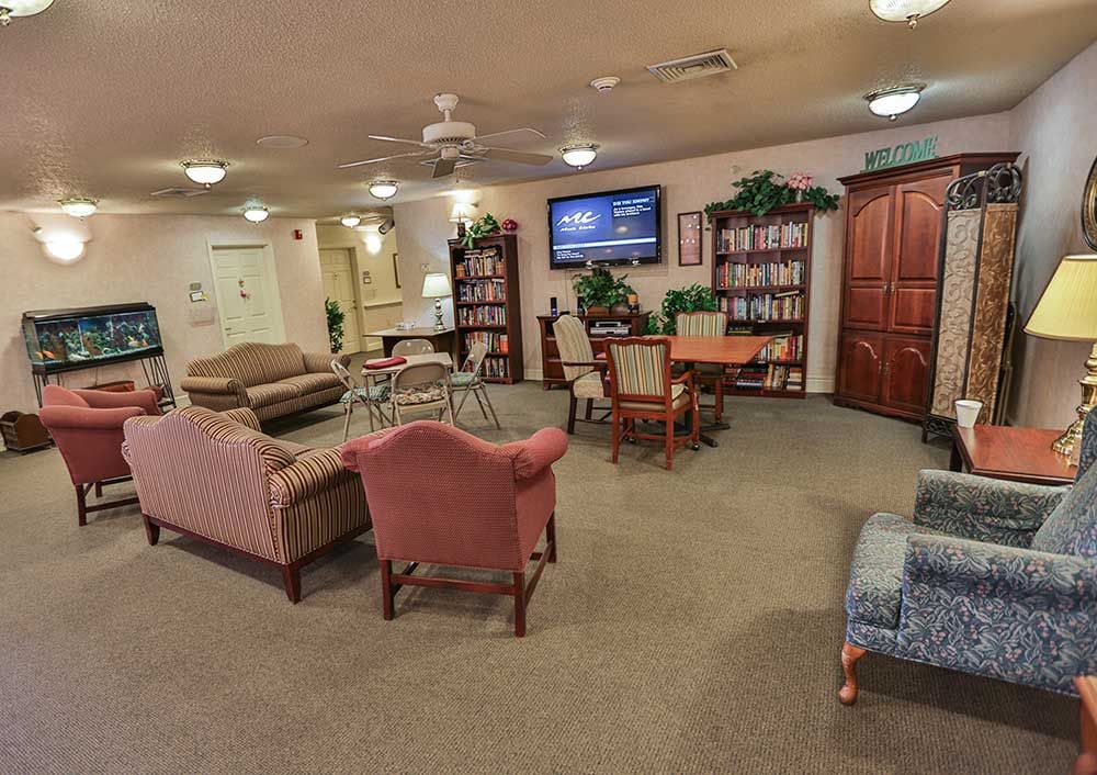 A cozy living room with sofas, chairs, bookshelves, and a television.