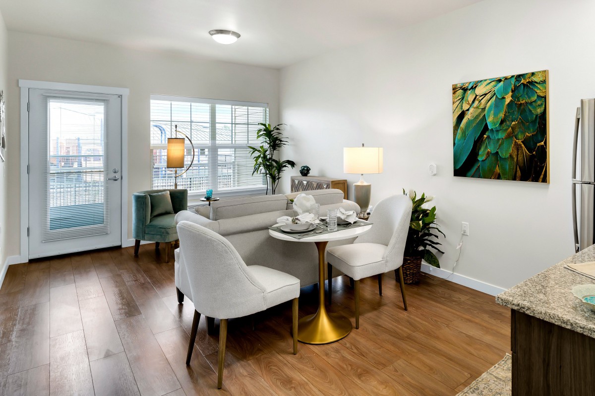 A modern living and dining area featuring stylish furniture, hardwood floors, and contemporary artwork.