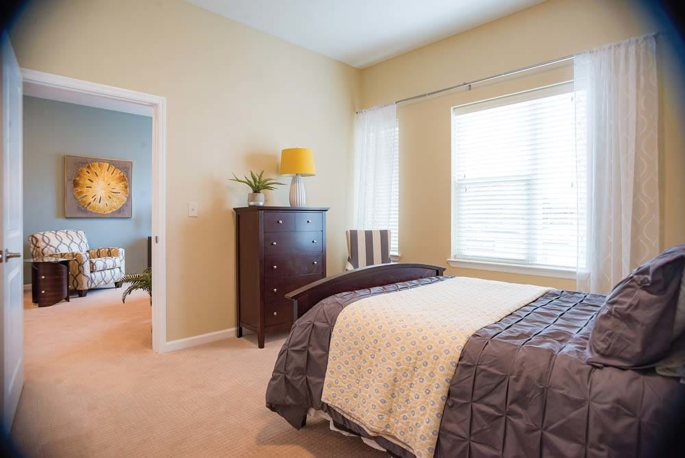 A cozy bedroom with a neatly made bed, a window letting in natural light, and stylish decor.