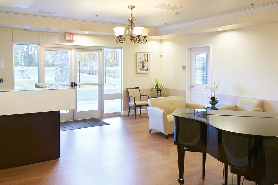 A welcoming lobby area featuring a piano, comfortable seating, and a chandelier.
