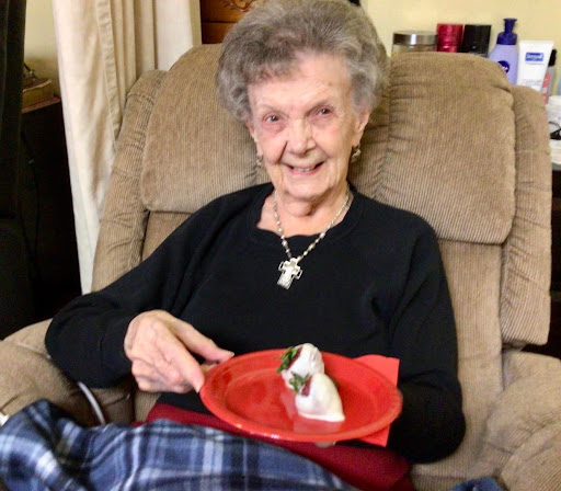 A cheerful senior woman enjoying a treat while seated comfortably in her living room.