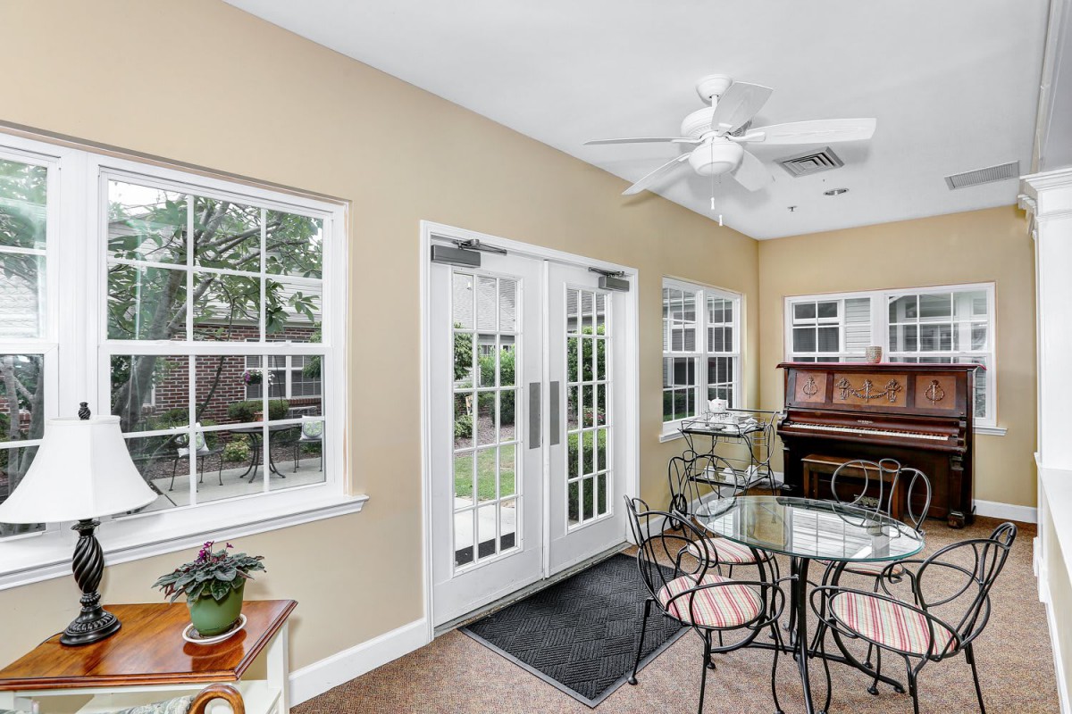 A bright sunroom features a dining set, piano, and large glass doors leading to the garden.