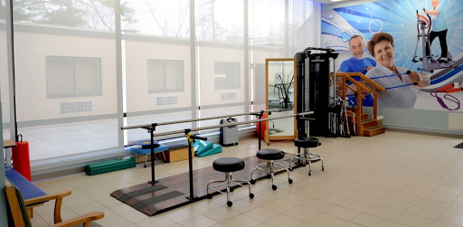 A well-equipped studio featuring a ballet barre, stools, and mirrors for fitness and rehabilitation exercises.