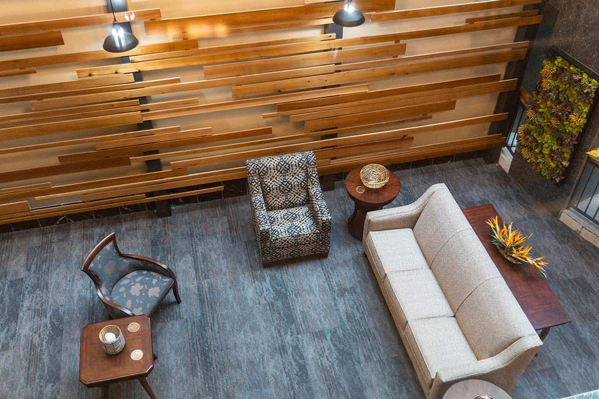 A modern living room with a patterned armchair, sofa, and wooden accent wall.
