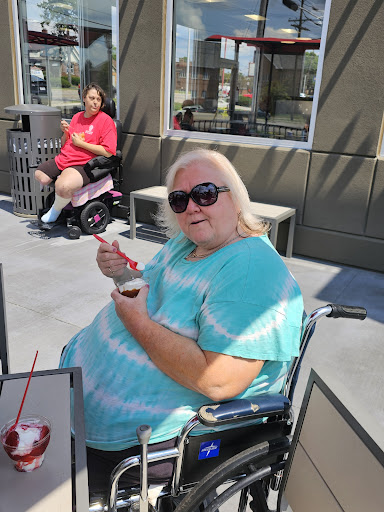 A woman enjoying a treat outdoors while seated in her wheelchair.
