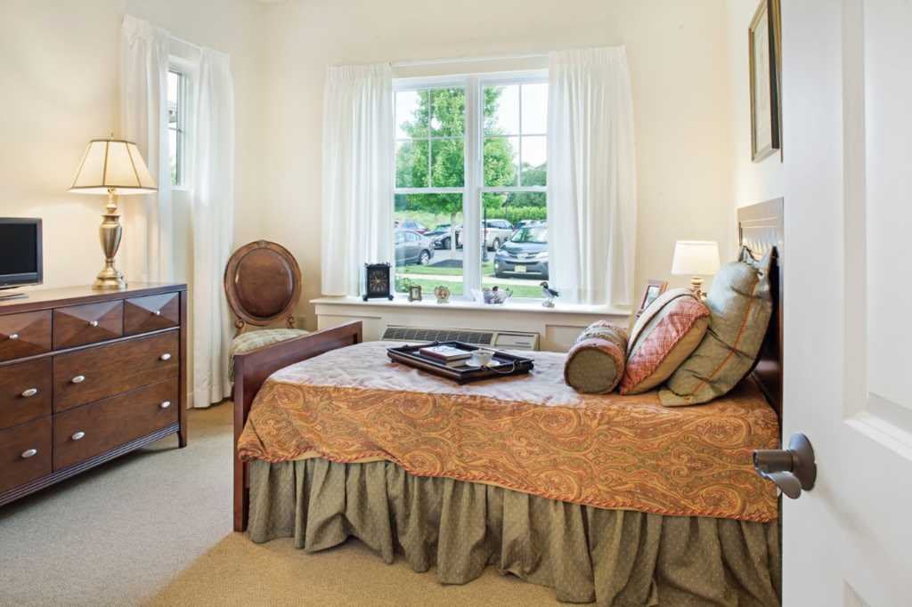 A cozy bedroom with elegant decor, featuring a bed near a large window that offers natural light.