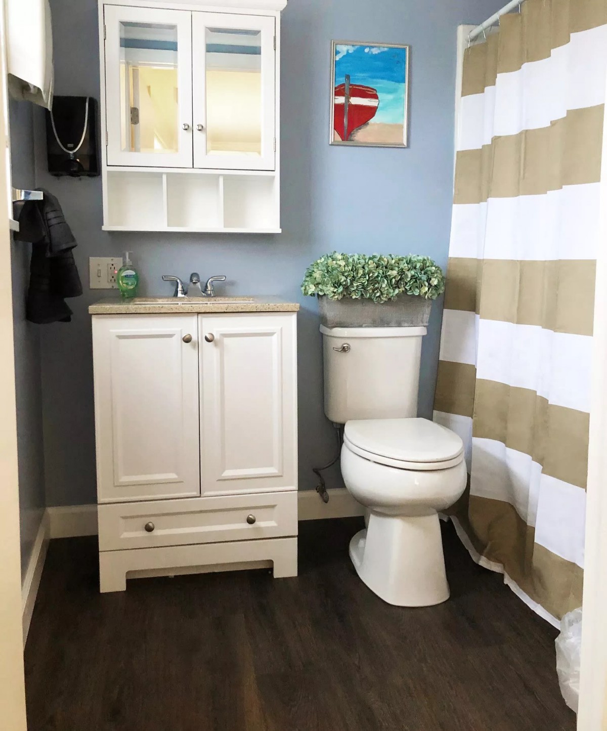 A modern bathroom with a white vanity, toilet, and striped shower curtain.