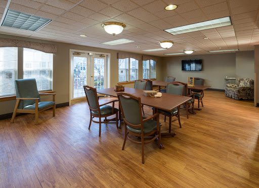 A spacious community dining area with wooden floors and ample natural light from large windows.