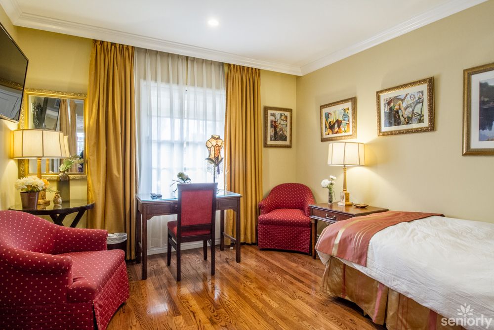 A cozy hotel room with a comfortable bed, desk, and warm lighting.