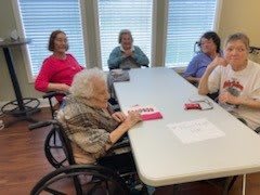 A group of elderly individuals gathered around a table for a meeting.