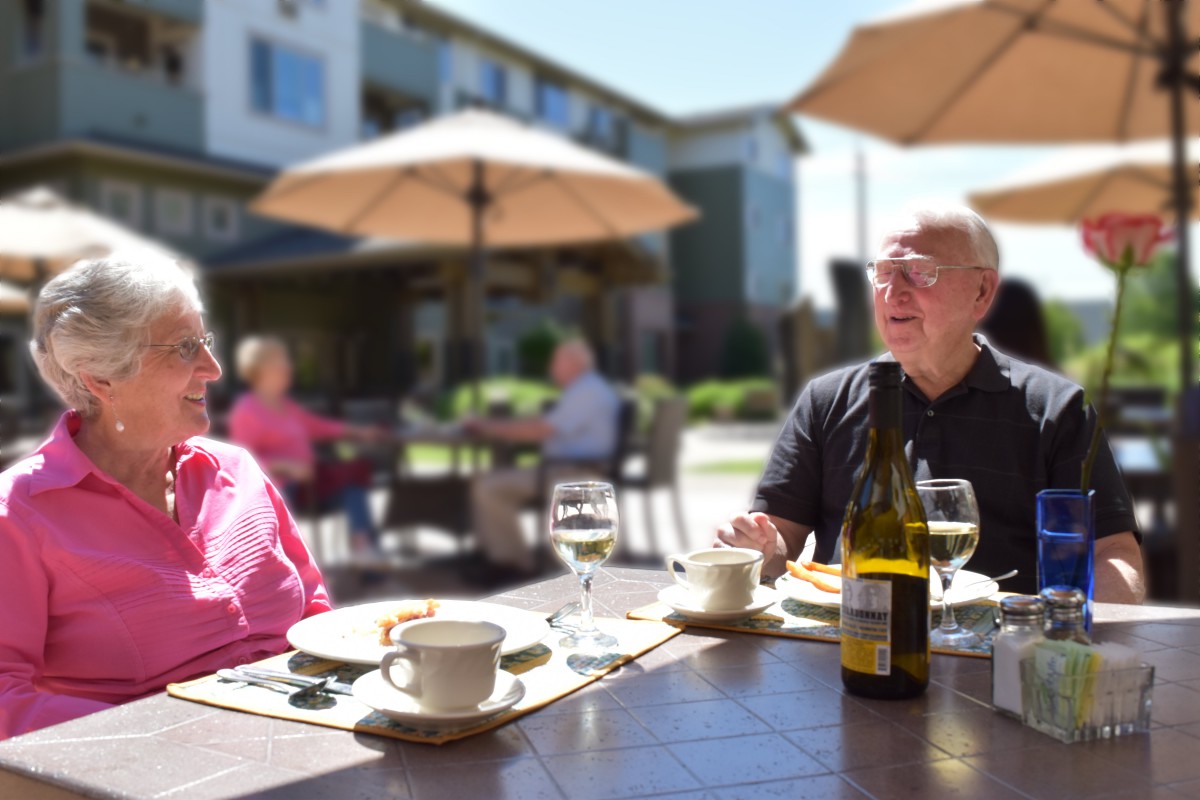 Two people enjoying a meal at an outdoor restaurant on a sunny day.