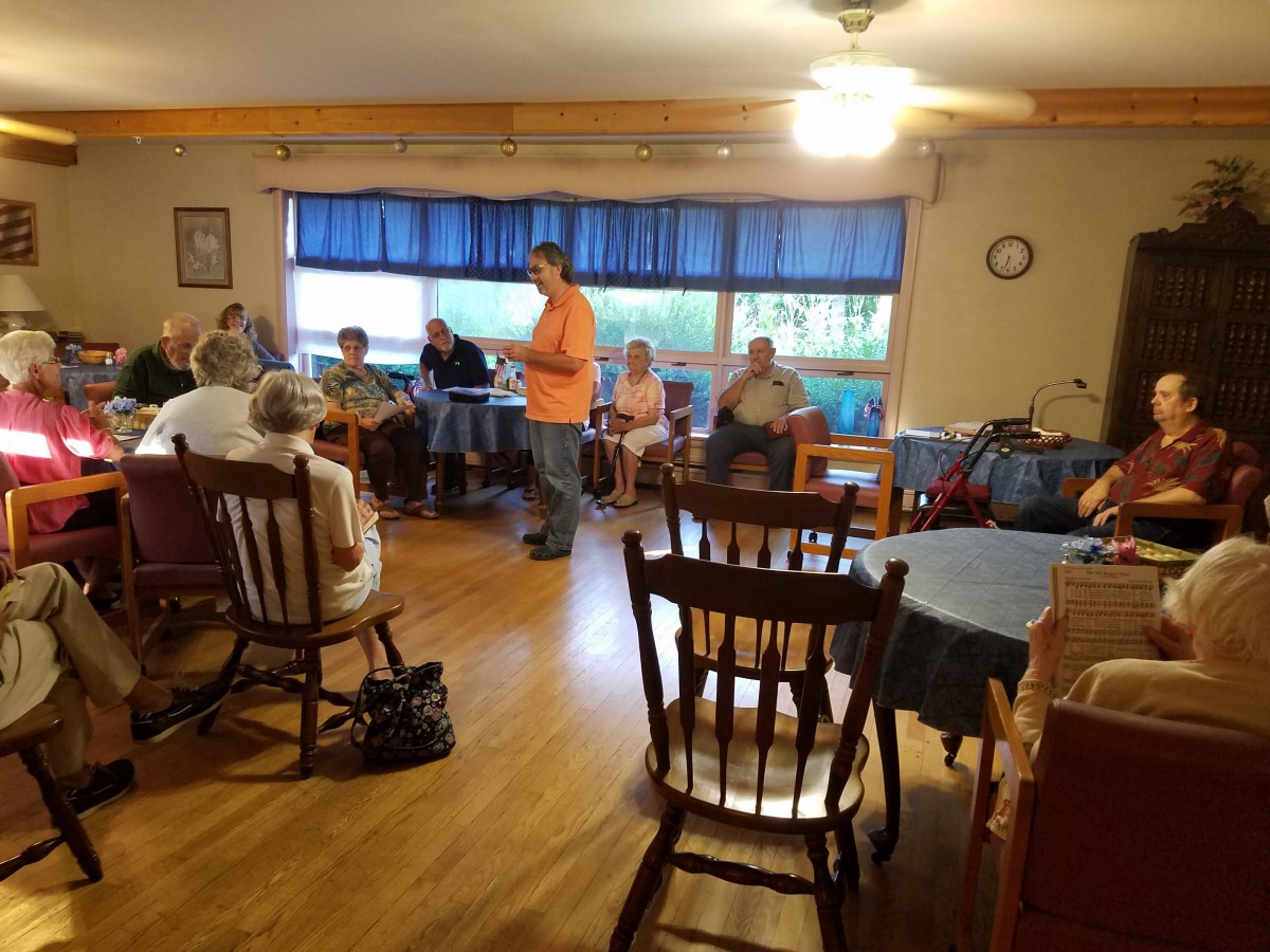 A community gathering indoors with people seated and engaged in conversation.
