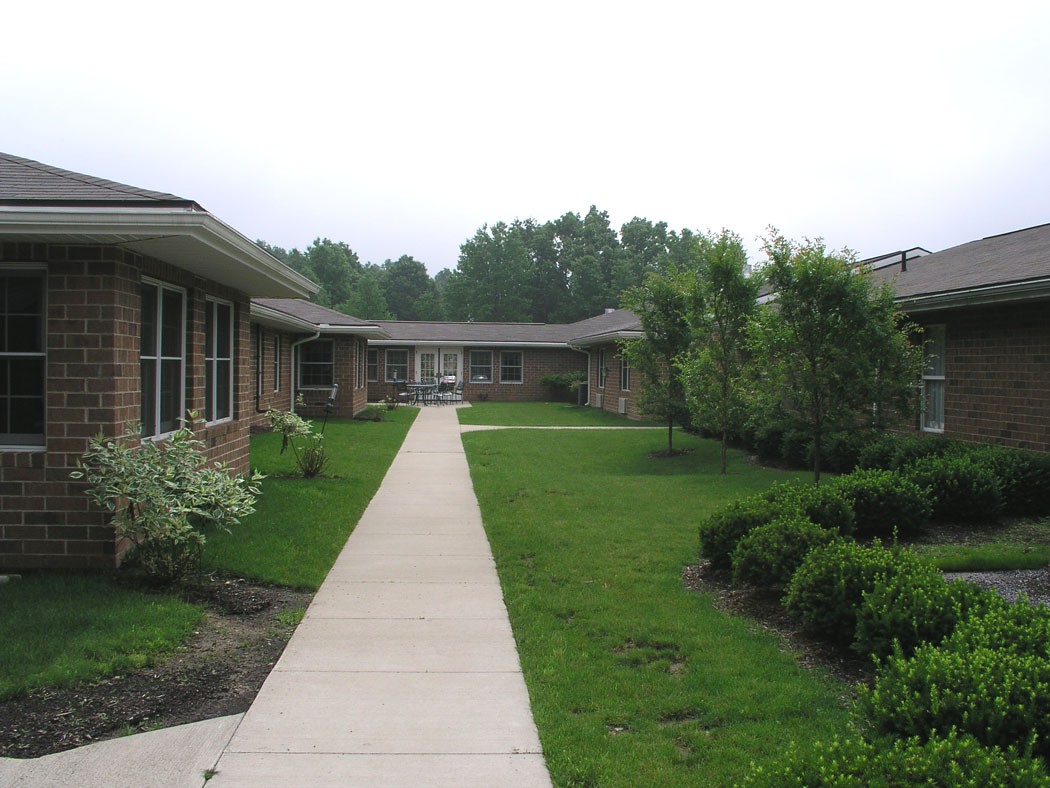 A peaceful courtyard with a central pathway surrounded by greenery and well-maintained landscaping.