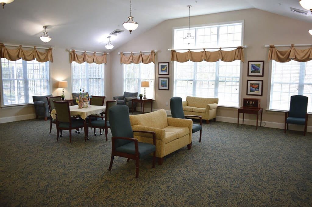 A cozy living room with sofas, chairs, and a table arranged near large windows.