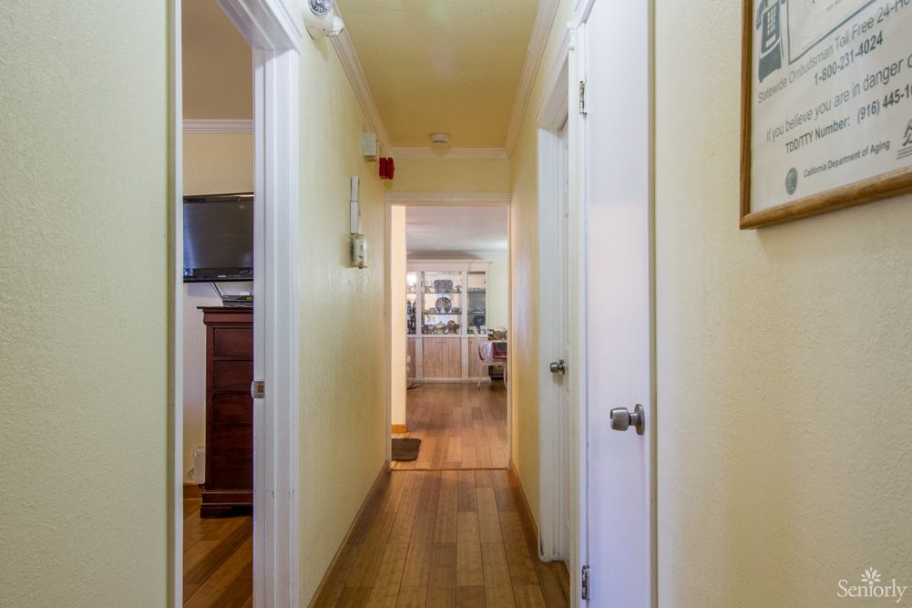 A bright hallway with a wooden floor and several doors leading to different rooms.