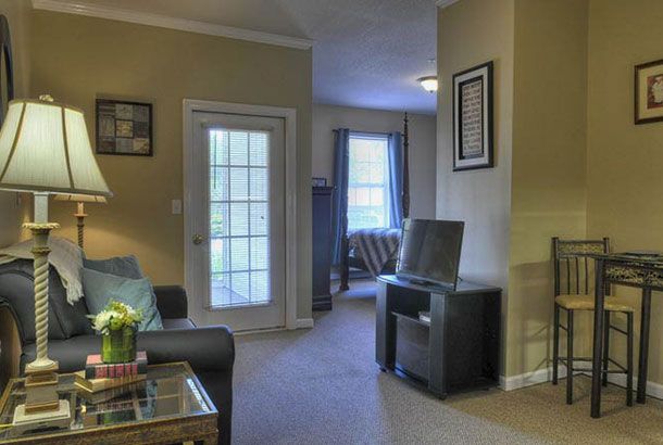 A cozy living room with a television, sofa, and a view of the adjacent room through a doorway.