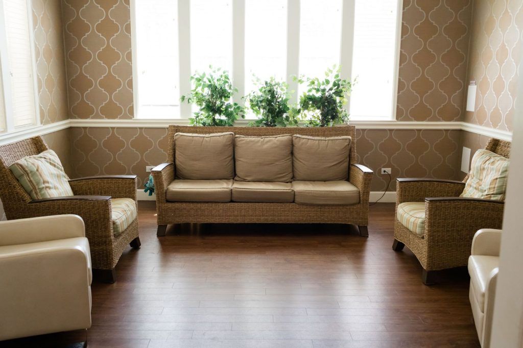 A cozy living room with a sofa, two armchairs, and indoor plants by the window.