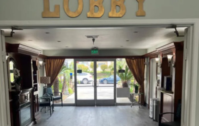 A hotel lobby area with seating and glass doors leading outside.