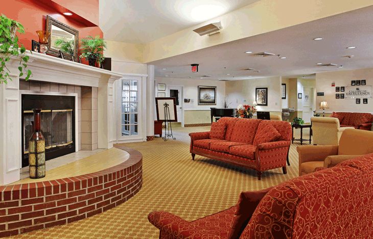 A cozy hotel lobby featuring a brick fireplace and red sofas.